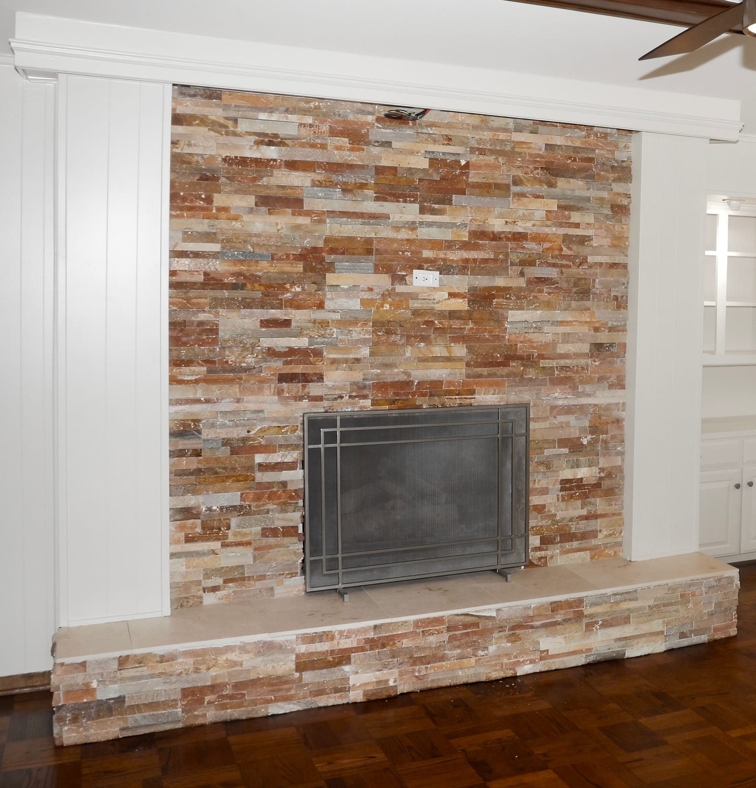 The same wall resurfaced in light stacked stone from floor to ceiling with a linear firebox