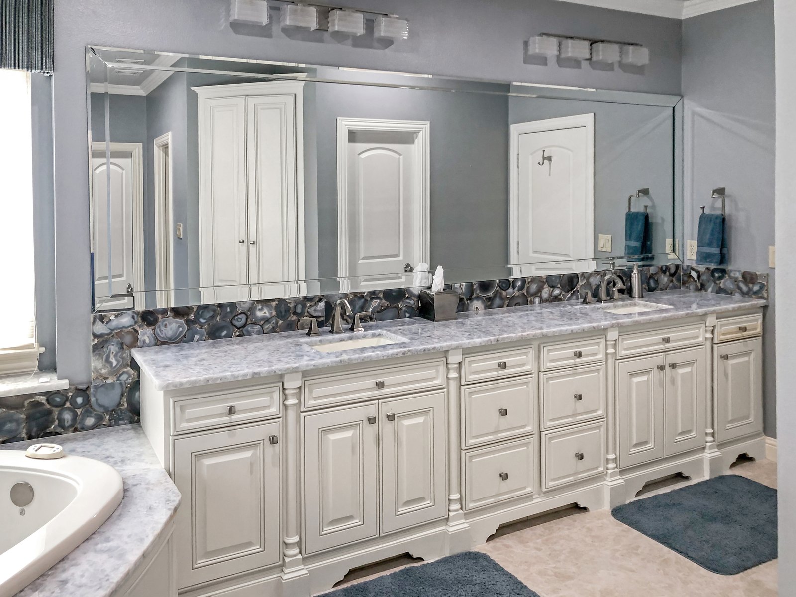 Long vanity with an agate mosaic backsplash and a framed mirror