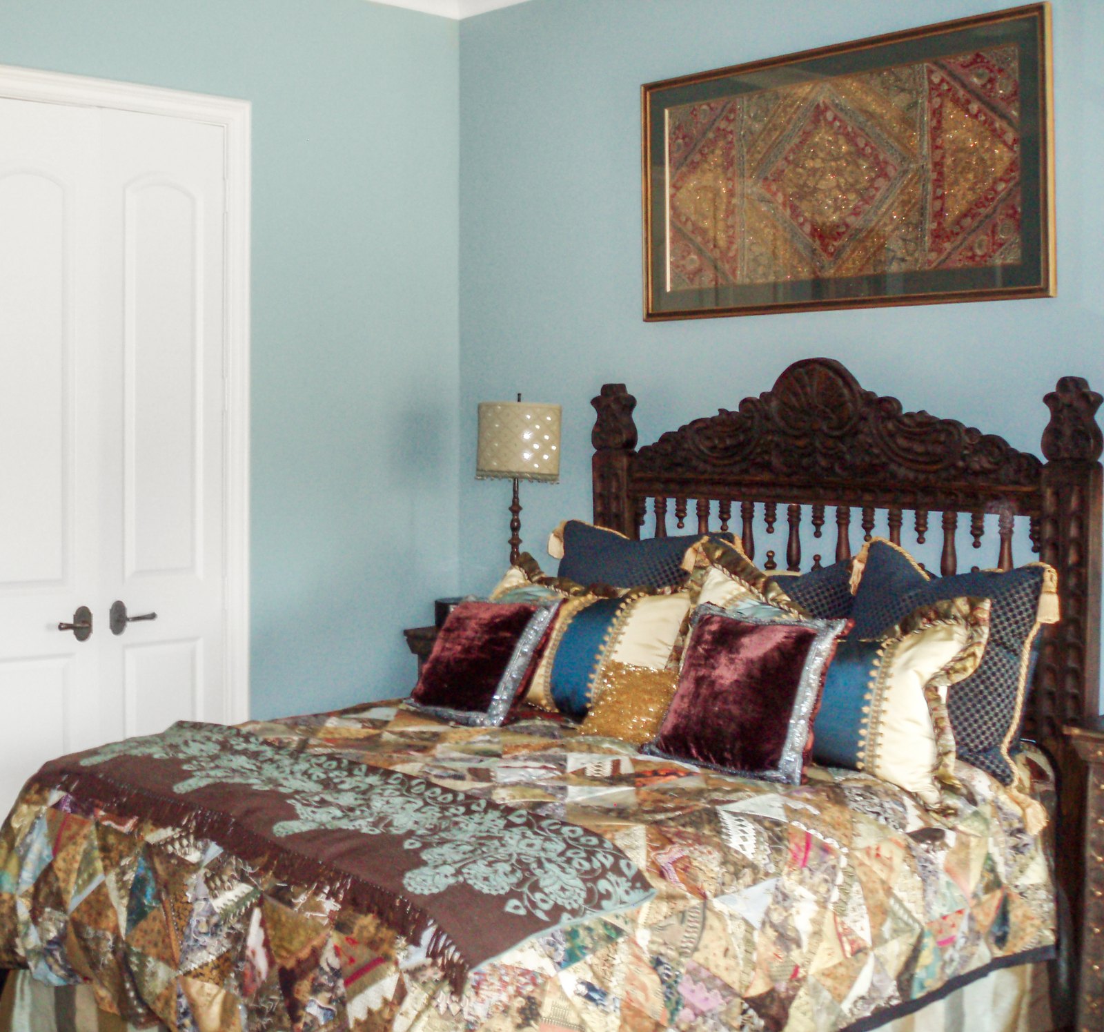 Bedroom with quilted headboard and international textiles