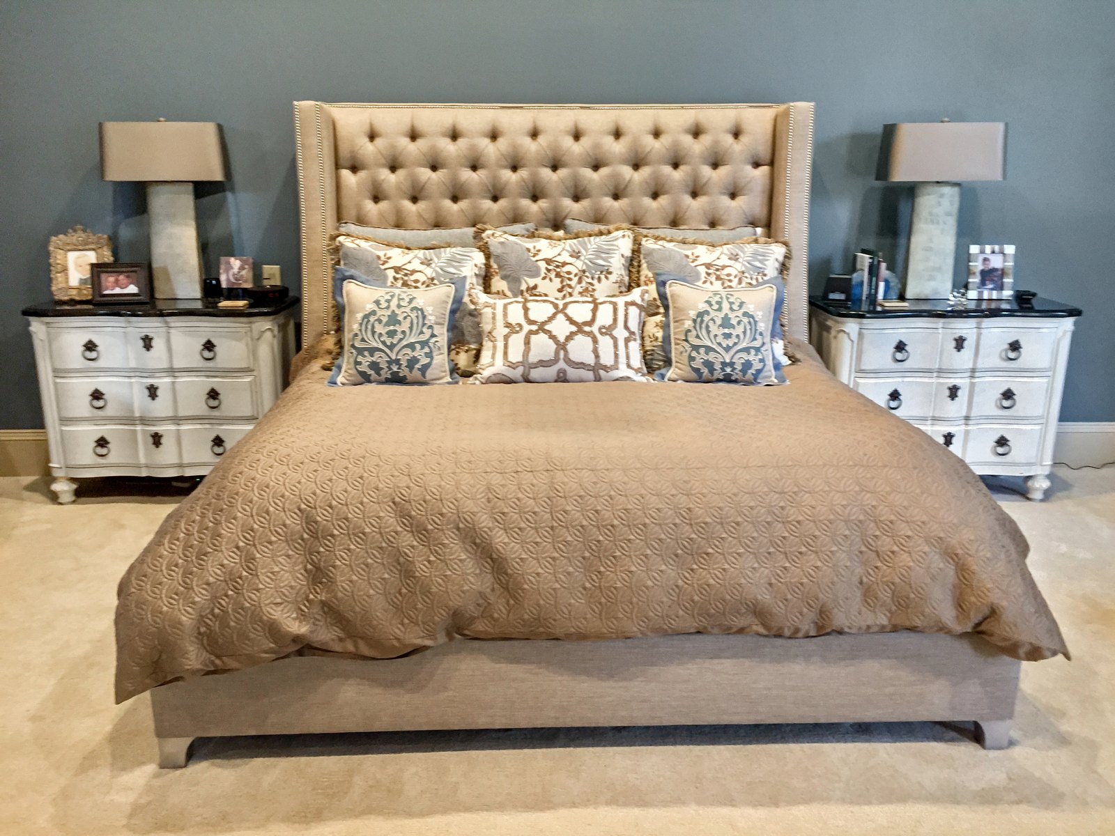 Master bedroom with a tall tufted headboard and mirrored chests