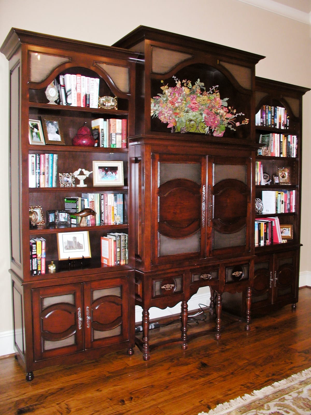 Carved dark-wood television cabinet with metal inlays flanked by bookshelves