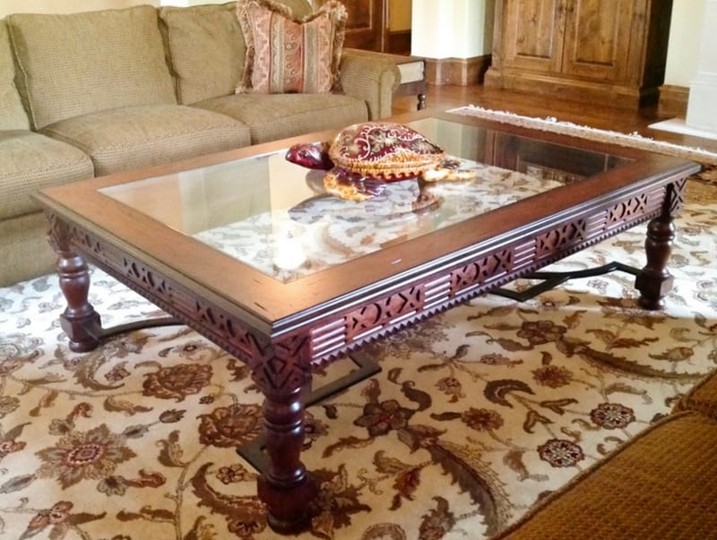 Custom carved cocktail table with an inset glass top