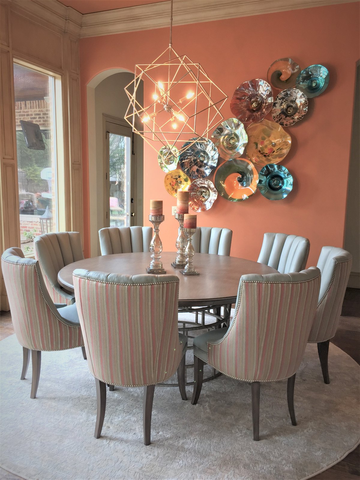 Dining room with a wall of colored glass plates and striped host chairs