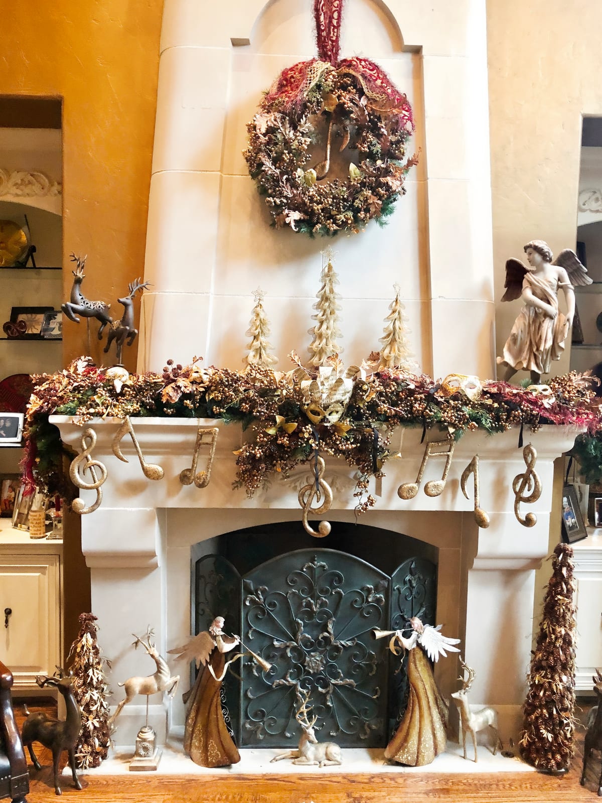 Mantel garland of gilded trees, ribbon and musical note ornaments above a fireplace