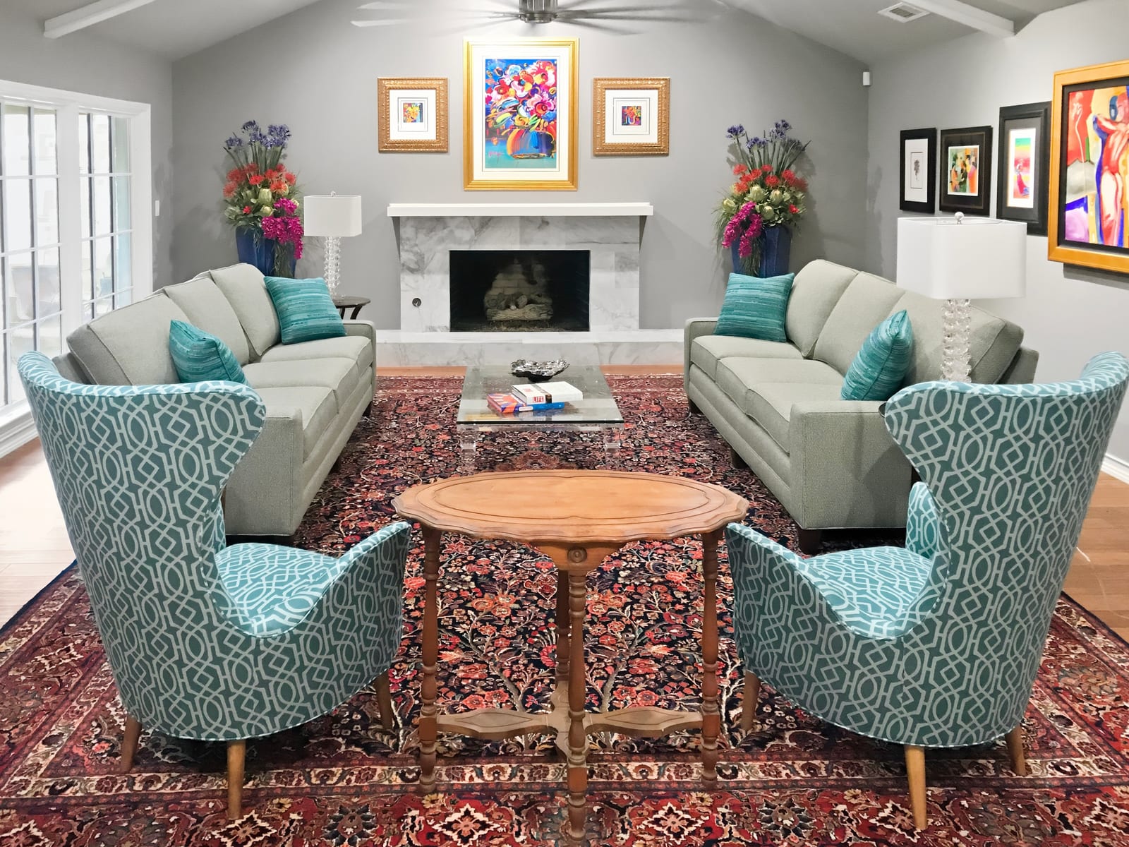 Family room with teal wing chairs, a white fireplace and bold framed art