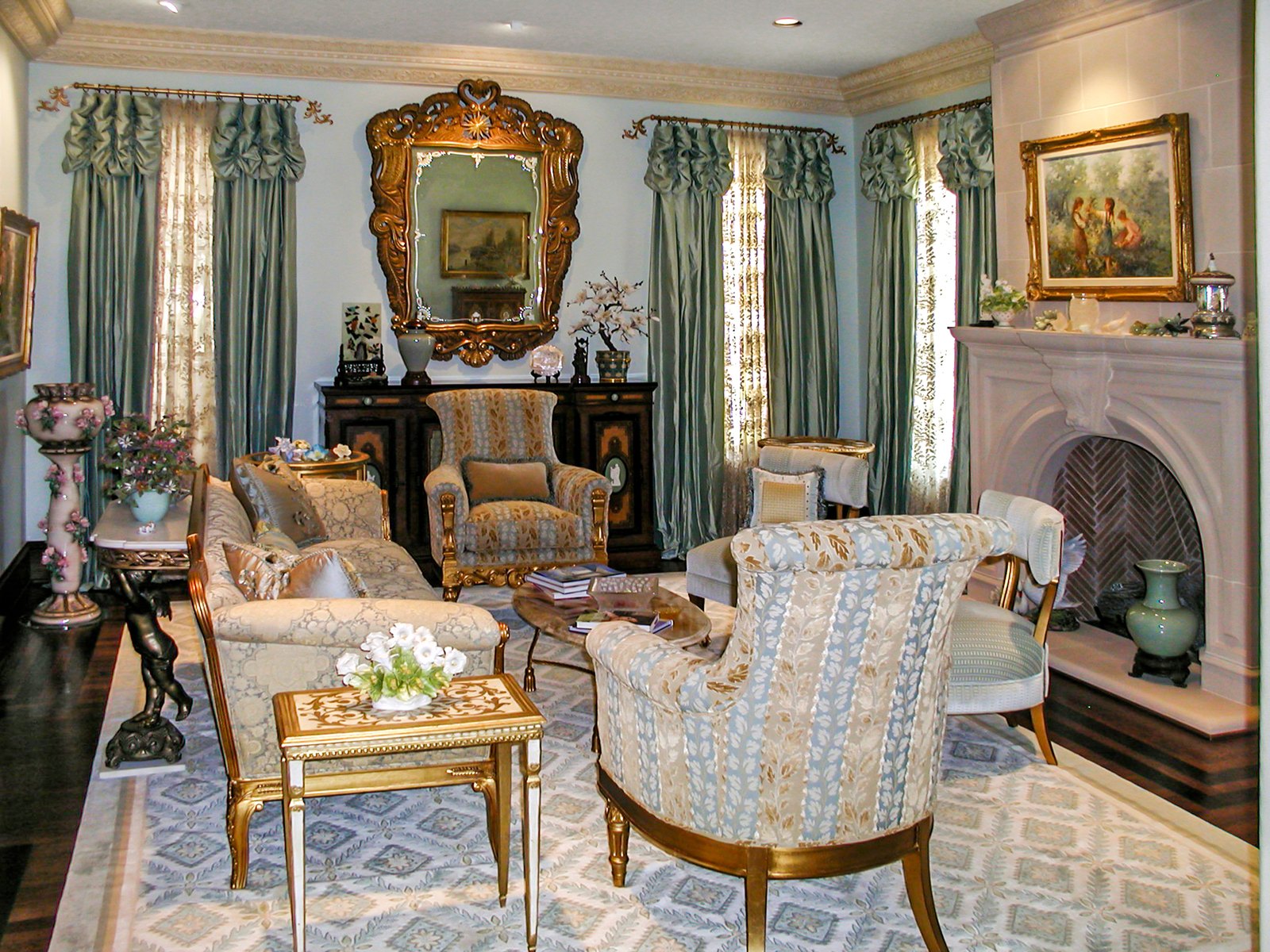 Formal living room with a gilded mirror, stone fireplace and patterned chairs
