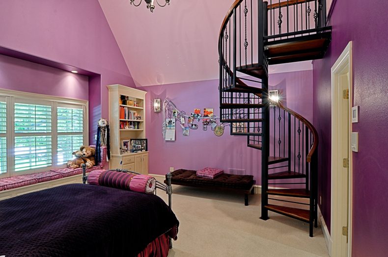 Bedroom with purple walls and a spiral staircase up to a loft