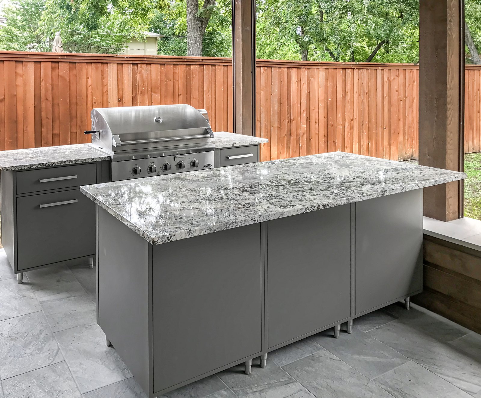 Covered outdoor kitchen with granite island and built-in grill