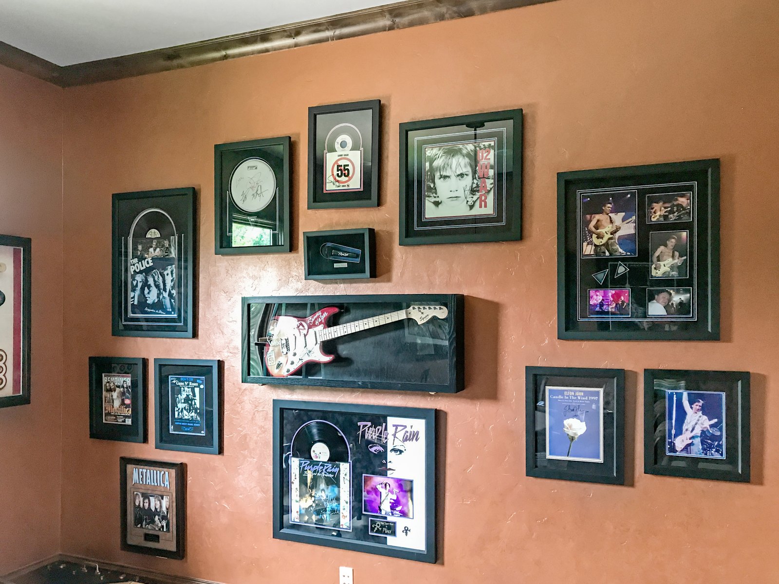 Memorabilia wall with framed art and guitars in a media room