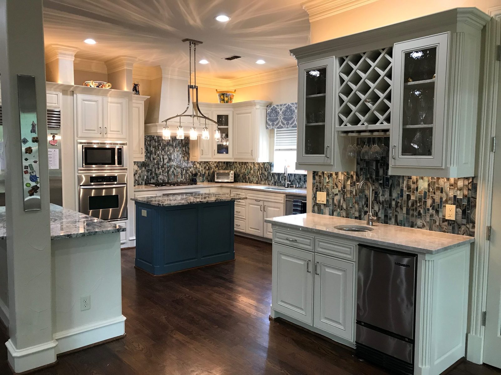 White kitchen with a blue island and mosaic backsplash by Chateau Concepts