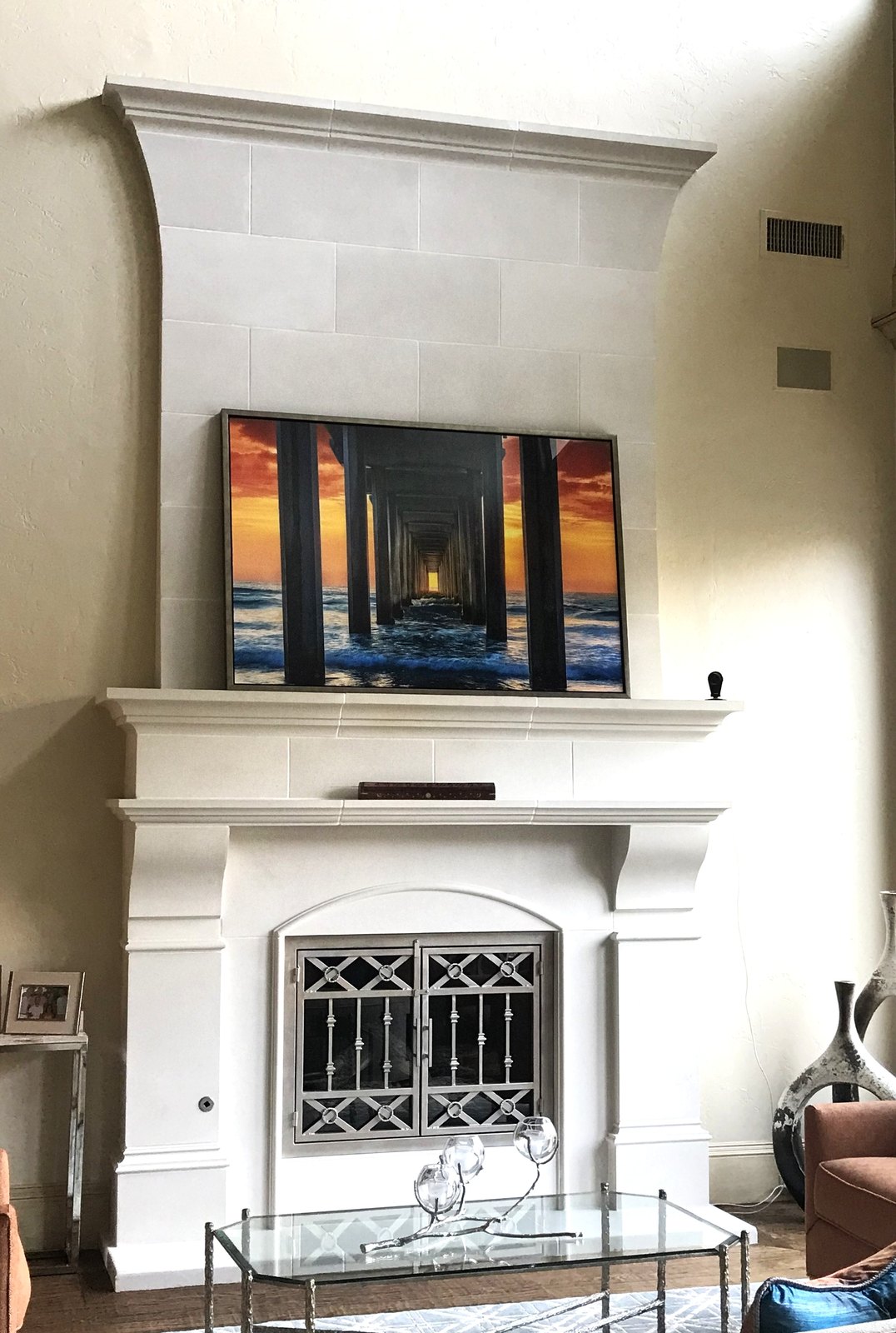 The same fireplace rebuilt in white cast stone, keeping the arched decorative firebox screen