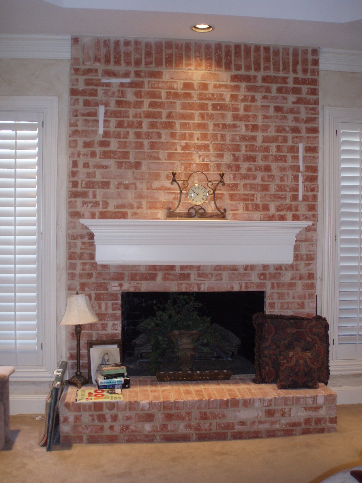 Floor-to-ceiling red brick fireplace with a plain white mantel shelf