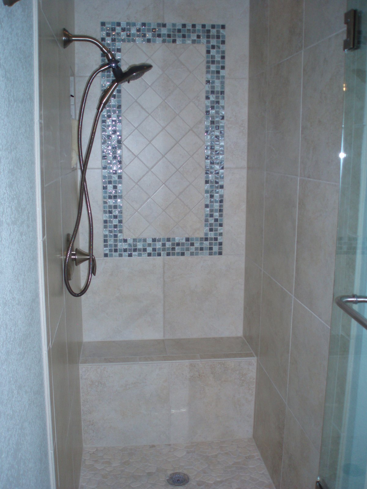 Renovated walk-in shower with a bench, handheld fitting and full-height tile