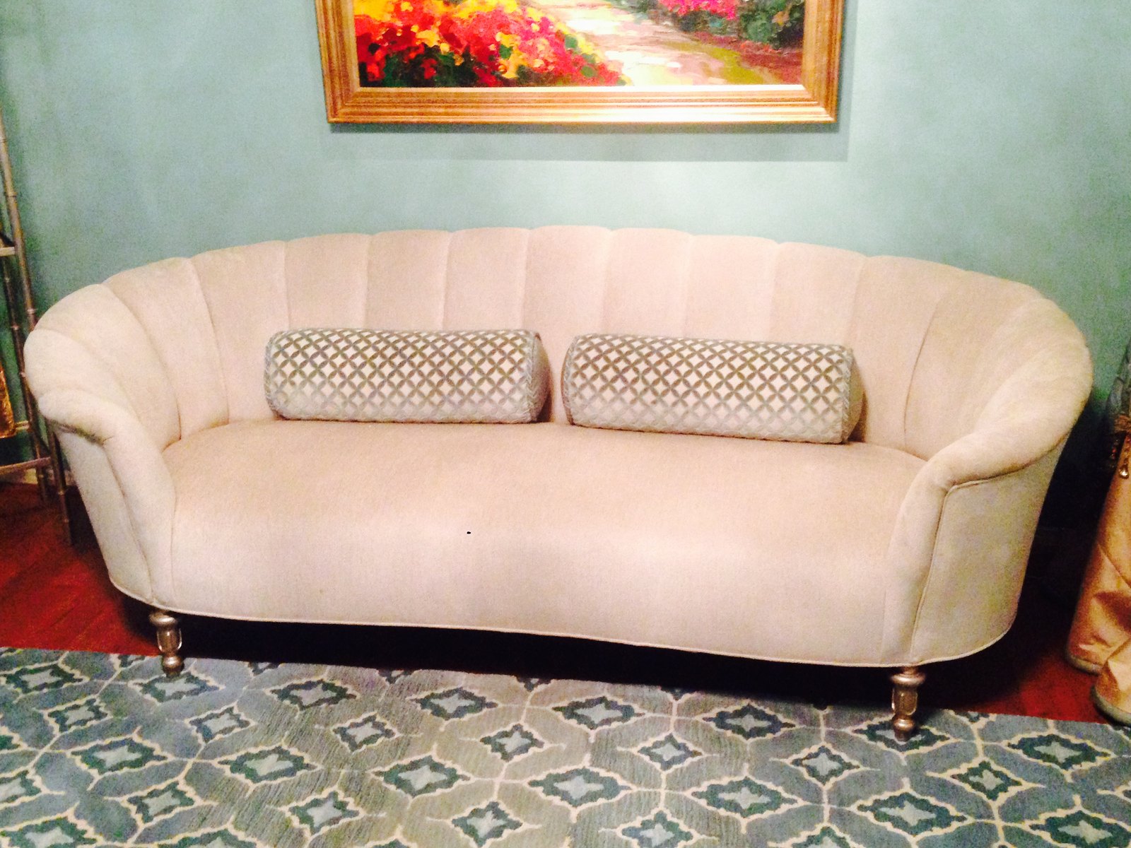 The same room with a cream curved sofa, a soft green wall and a new patterned rug