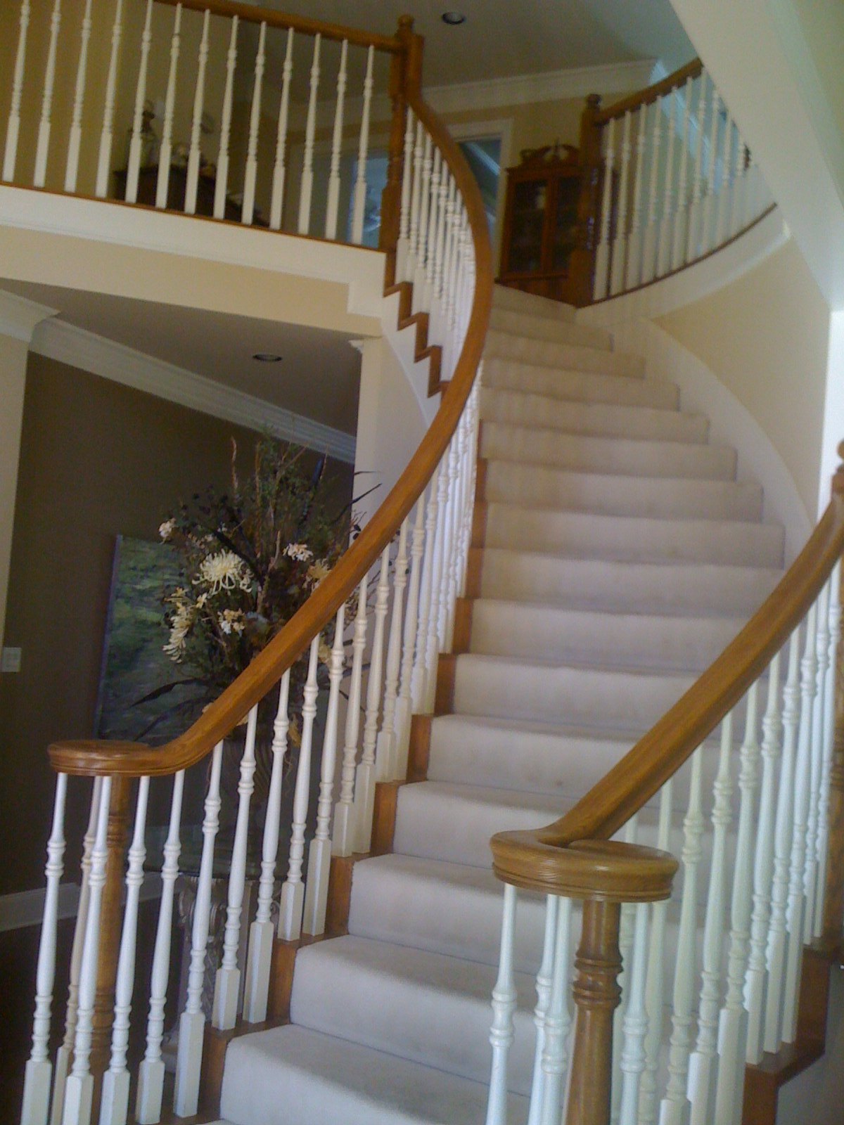 Curved staircase with white turned spindles, an oak handrail and carpeted treads
