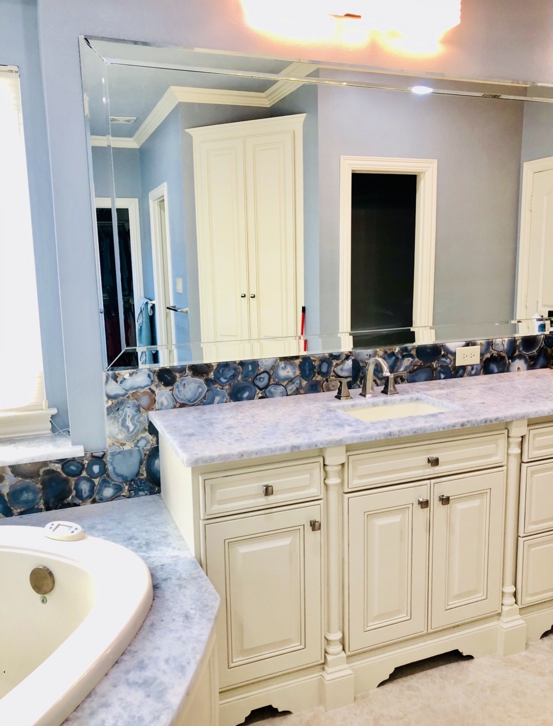Long vanity with an agate mosaic backsplash and a framed mirror