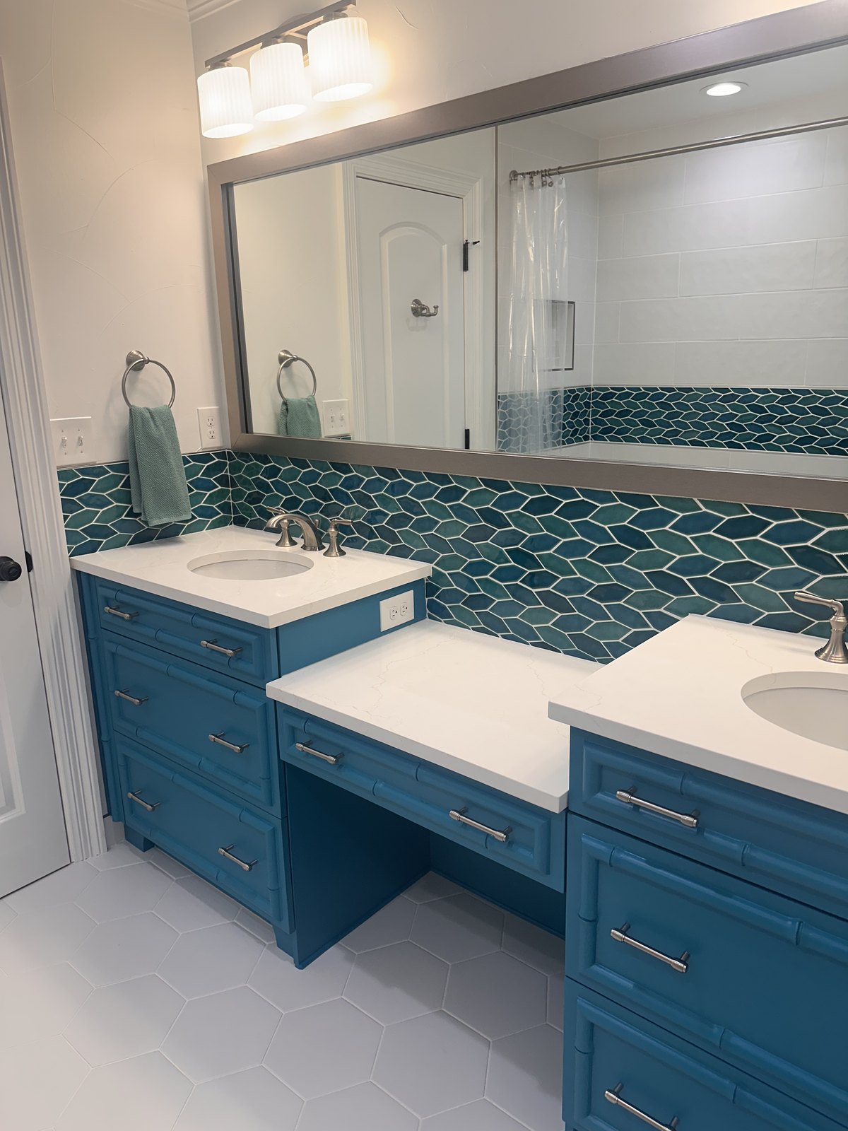 Shared bathroom with twin vanities in teal and a fan-tile backsplash