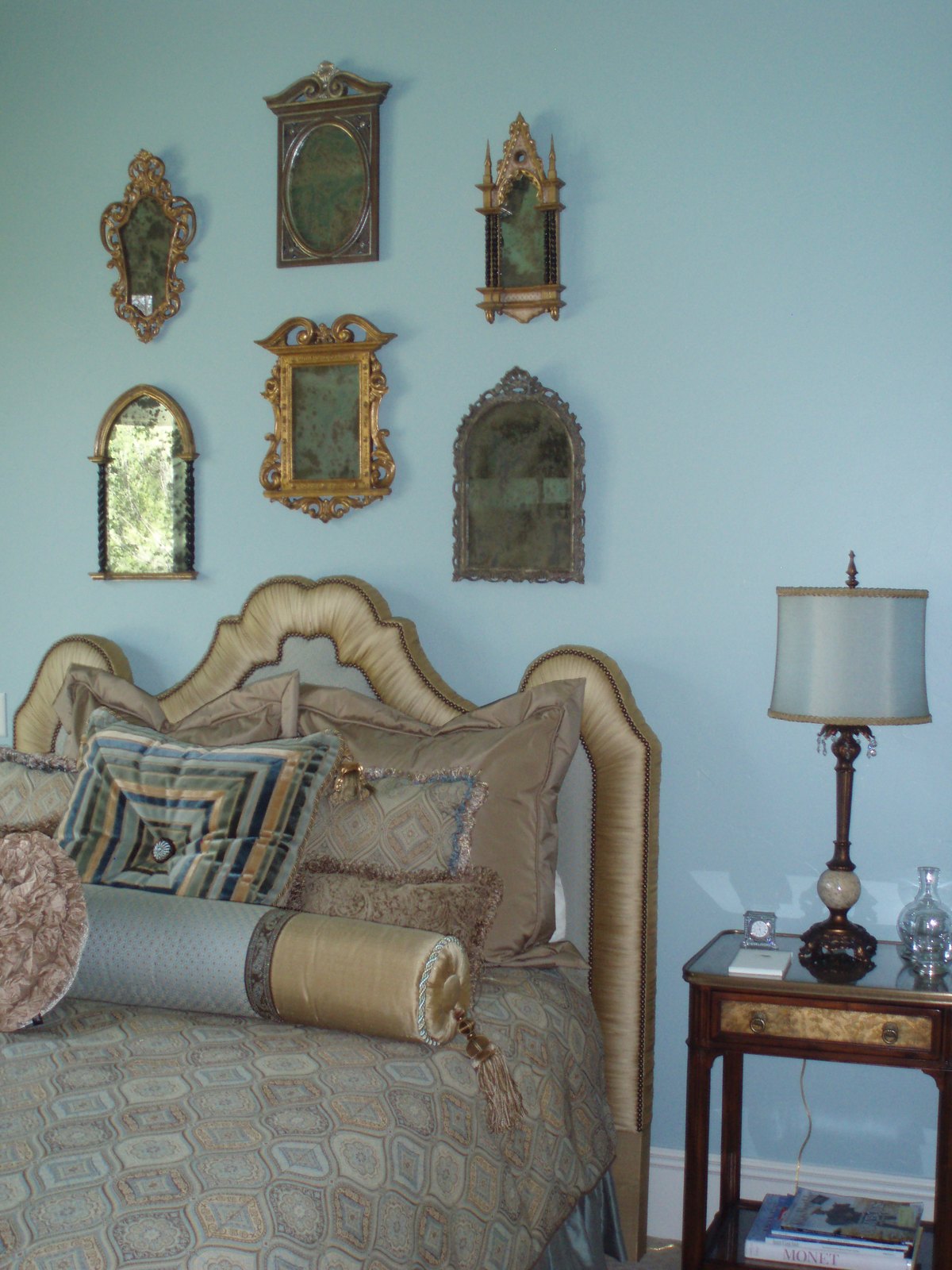 Bedroom with antique wall mirrors above an upholstered bed