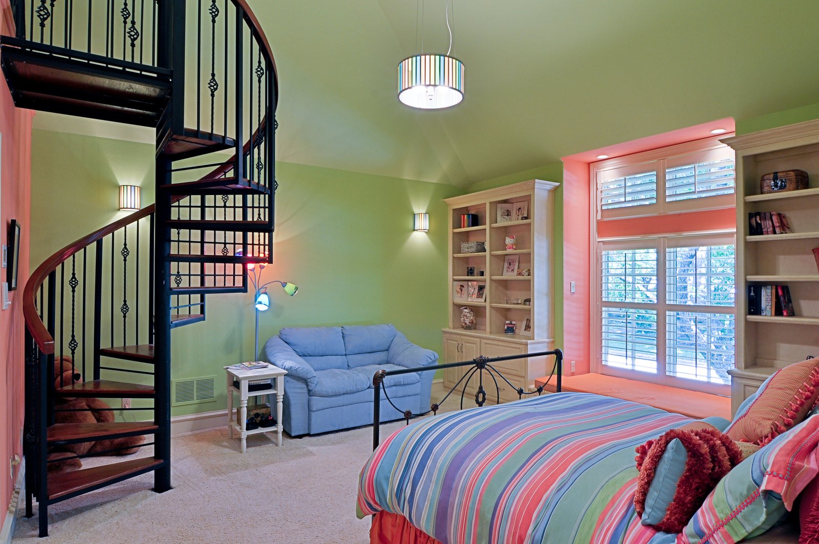 Loft bedroom with striped bedding and a spiral staircase