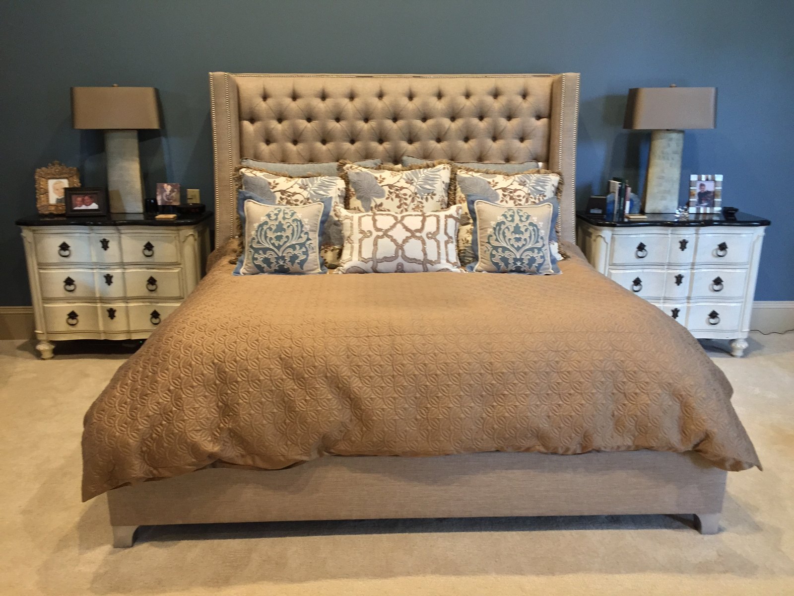 Master bedroom with a tall tufted headboard and mirrored chests