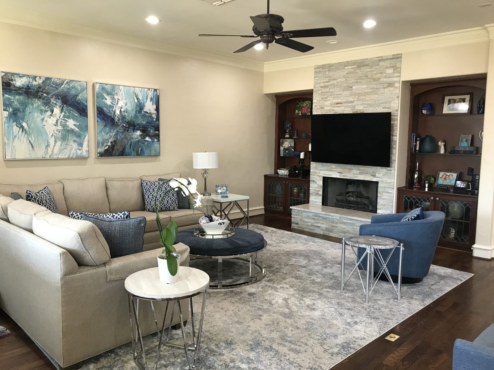 Family room with a stone fireplace and layered blue seating designed by Chateau Concepts