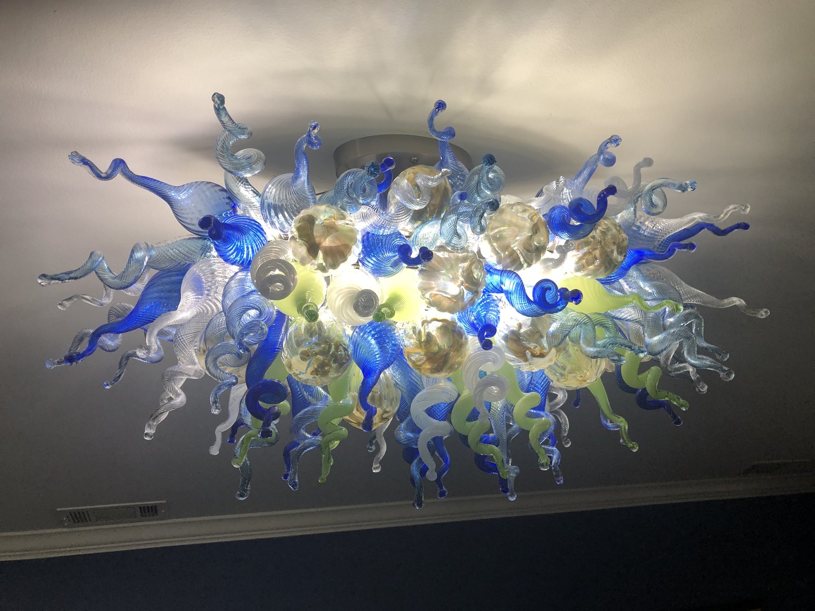 Hand-blown glass chandelier in blue, green and amber mounted to the ceiling