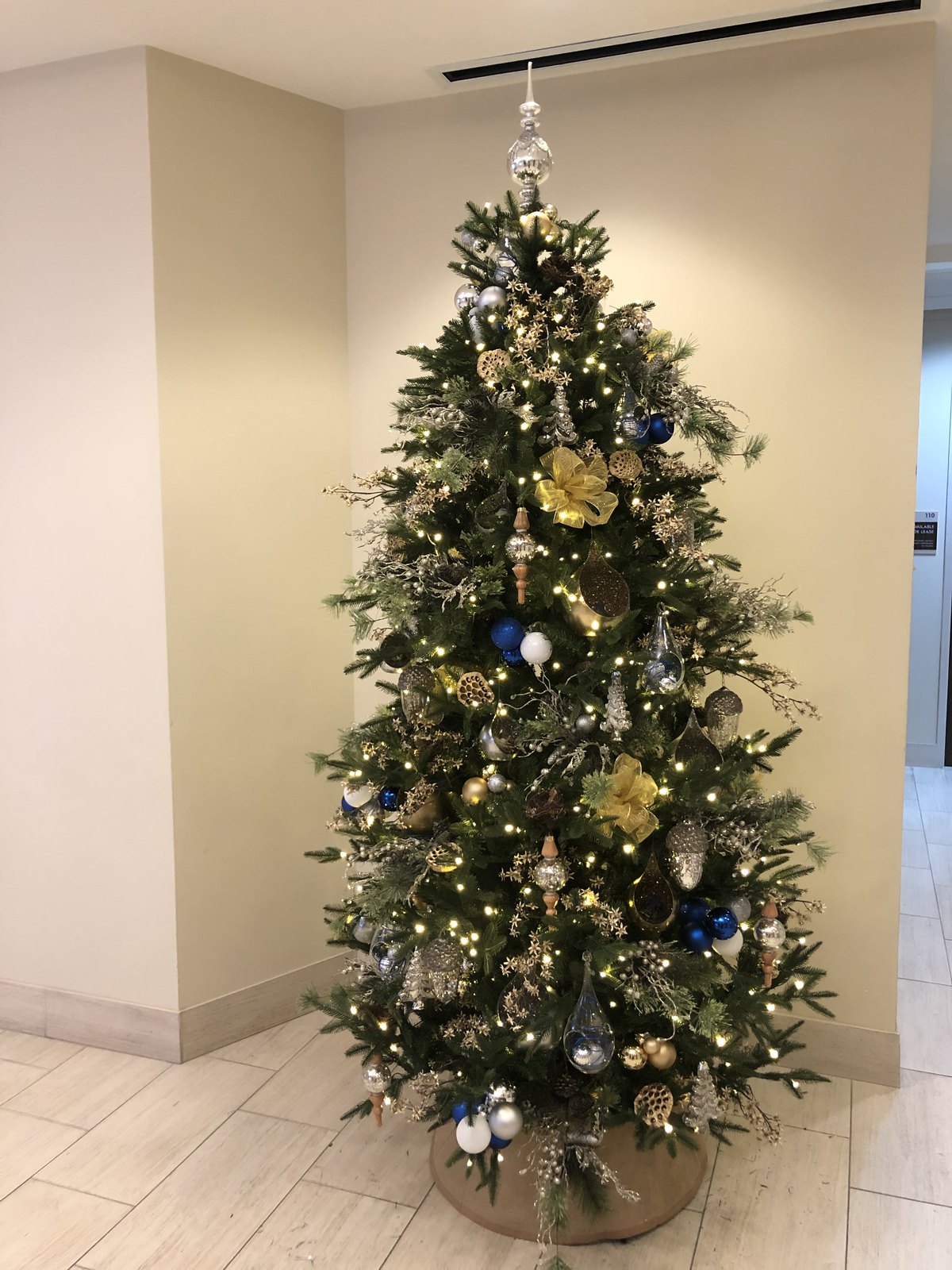 Office lobby Christmas tree in gold, silver and blue with woodland ornaments