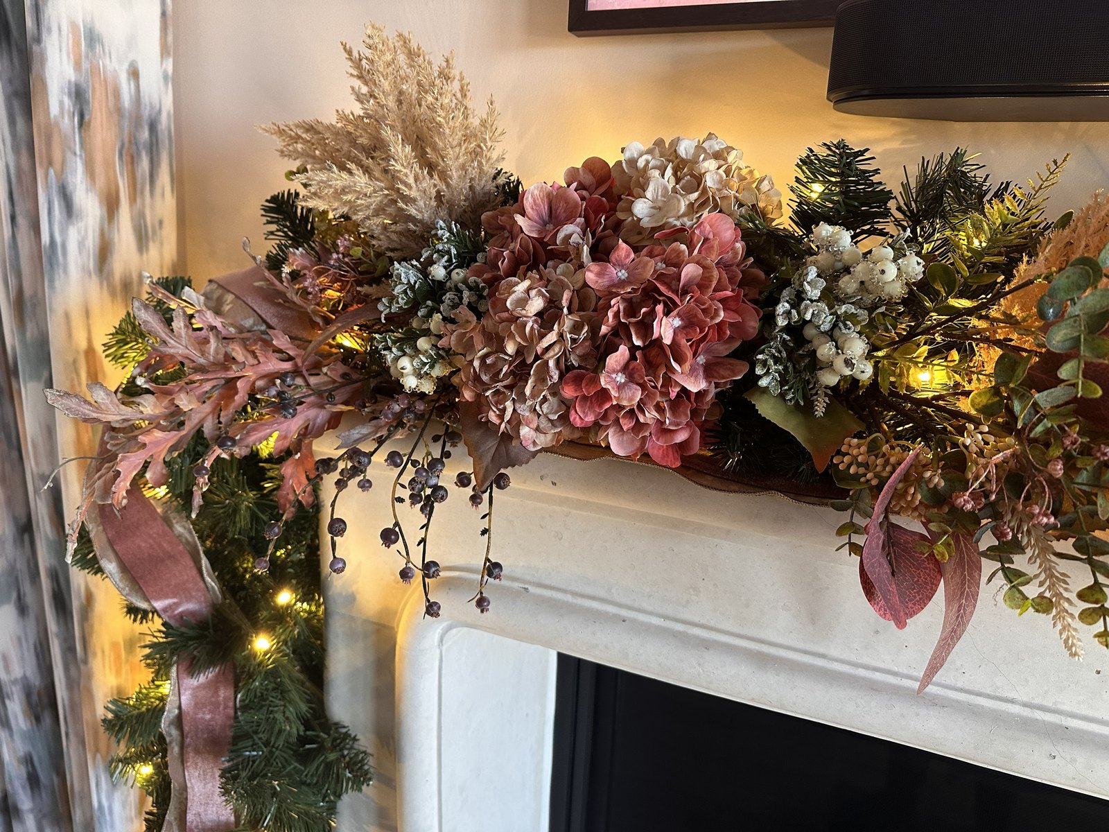 Close view of blush hydrangea, pampas grass and pink ribbon in a lit garland