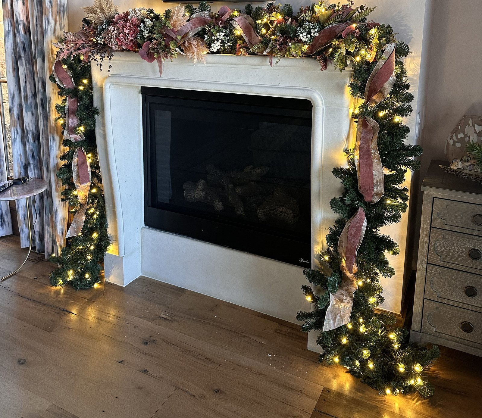 Lit garland in blush and green running the full width and down both sides of a fireplace