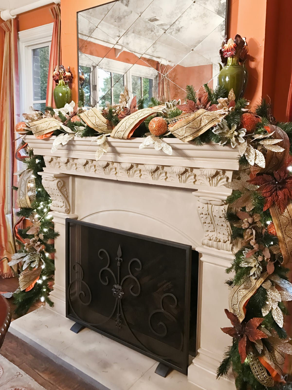 Carved stone fireplace framed by a full evergreen garland in a warm terracotta room
