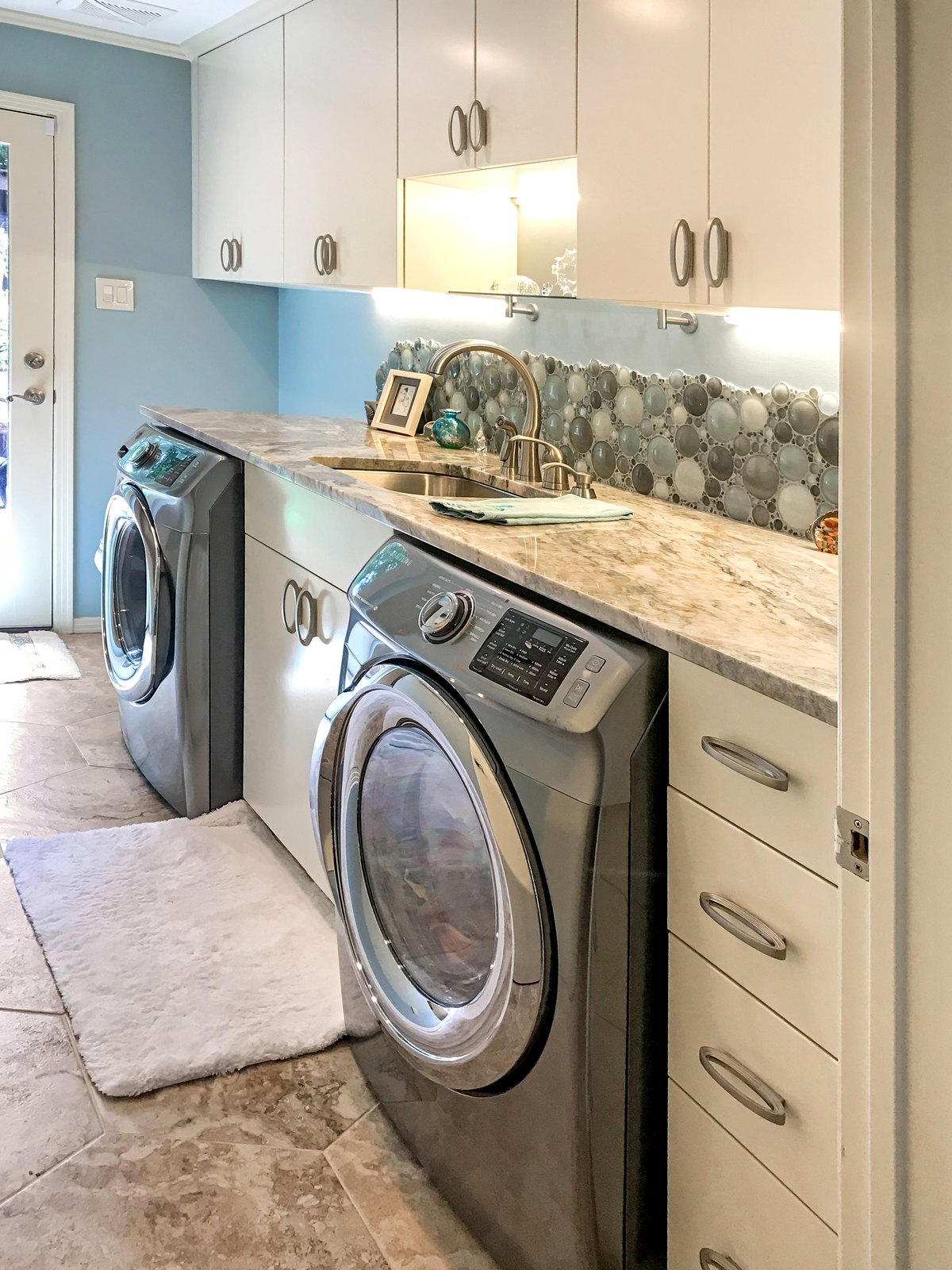 Laundry and pool bath with custom cabinetry, stone counters and a bubble-glass mosaic backsplash