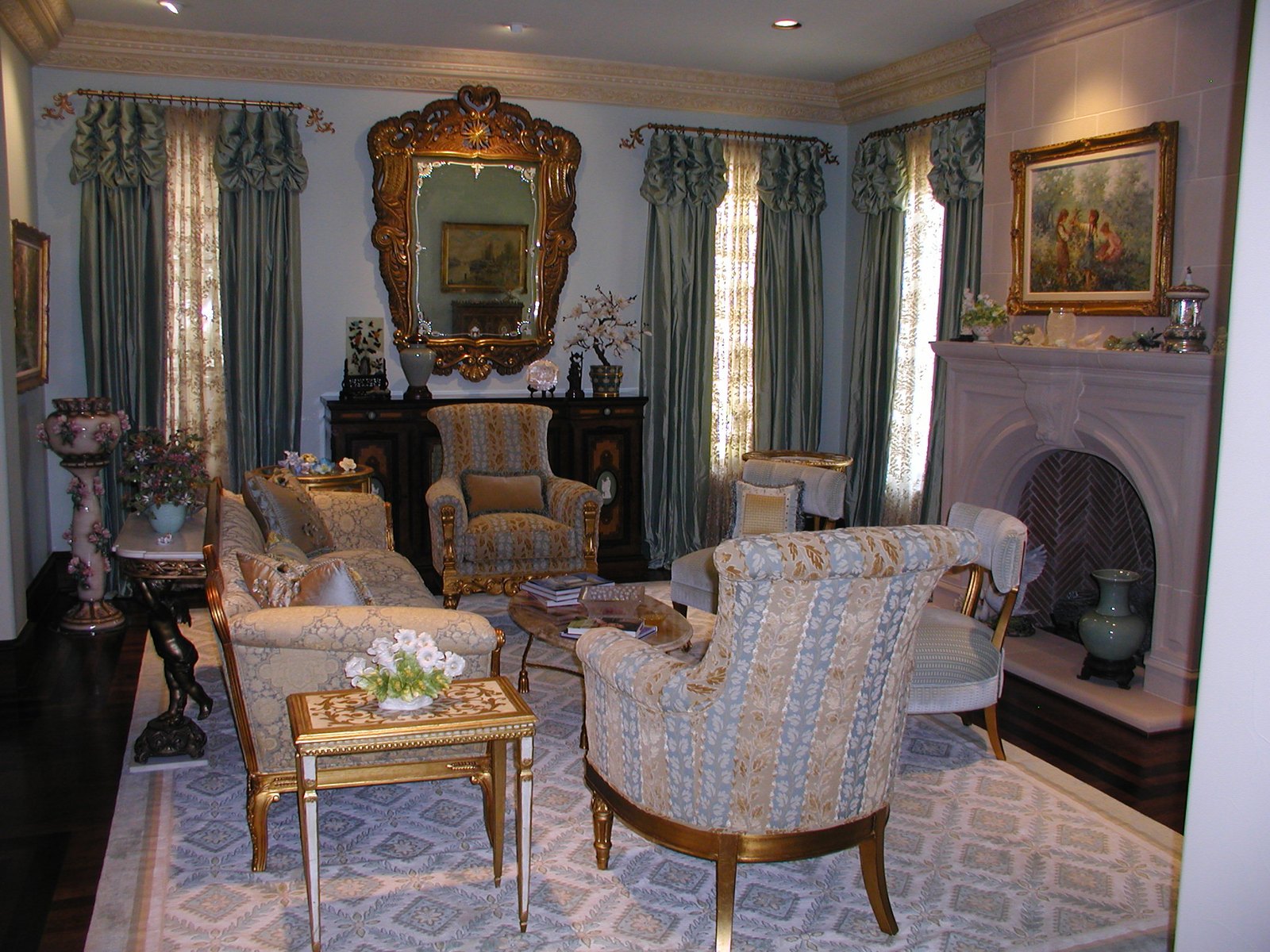 Formal living room with a gilded mirror, stone fireplace and patterned chairs